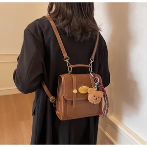Détail du sac à dos rétro marron avec charm ours en peluche et étiquette métallique