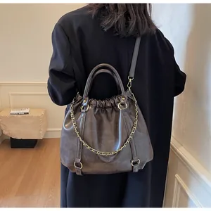 Rear view of model holding retro brown pleated PU handbag with gold chain detail