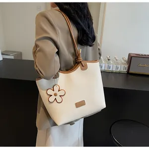 Detail of cream bucket bag with lychee texture leather, floral charm and brown handle