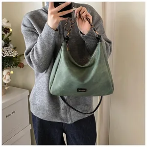 Detail of dark green suede hobo bag featuring fashion label and chain woven strap