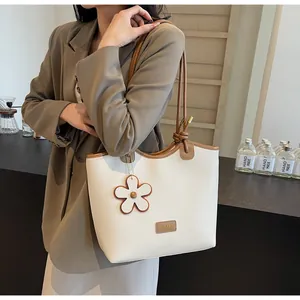 Detailed macro view of the beige lychee pattern leather and floral charm on the handbag