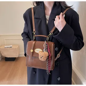 Détail du sac à dos vintage marron multifonction avec breloque ours et coutures en cuir