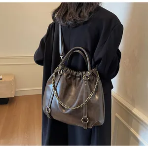 Detail of vintage brown pleated faux leather bag with gold chain and crossbody strap