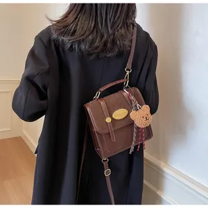 Détail du sac bandoulière marron en cuir et suède avec charmant petit ours en peluche