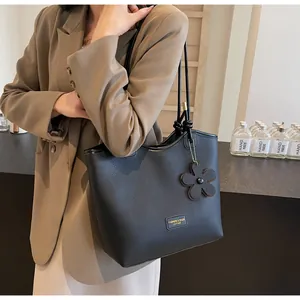 Detail of black lychee grain leather bucket bag with floral charm and brand plaque