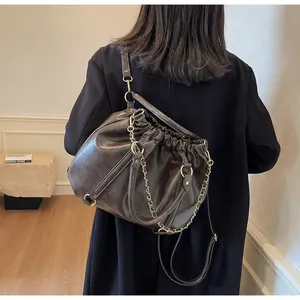 Detail of dark brown pleated cloud bag with soft leather texture and golden metal chain