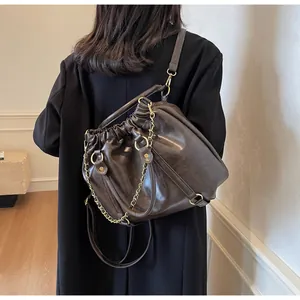 Detail of dark brown pleated leather bag with gold chain strap on model back