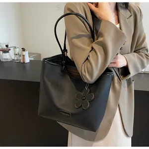 Close-up of black litchi grain leather bucket bag featuring a brown flower charm