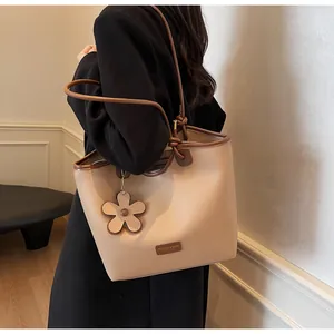 Detail of lychee pattern leather tote bag with flower charm and long shoulder strap