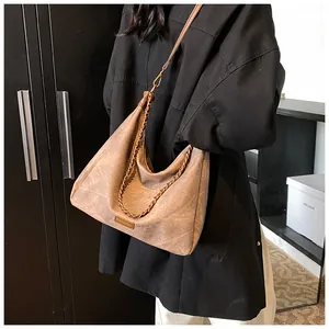 Detail view of retro suede tote bag with bronze metal chain and adjustable strap