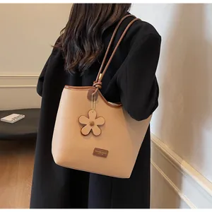 Detail of khaki lychee grain leather tote bag with floral charm and slim strap