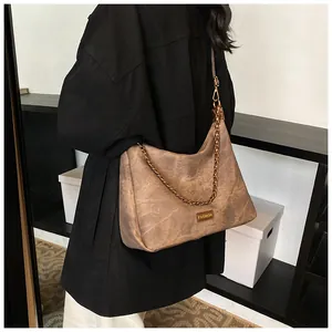 Detail of vintage brown suede tote featuring gold chain link and fashion logo plaque