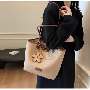 Detail view of beige bucket bag with brown contrast straps and flower charm