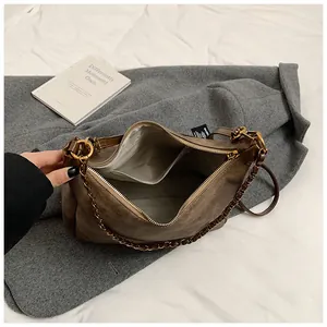Detail view of the brown faux suede tote bag showing zipper closure and bronze chain strap