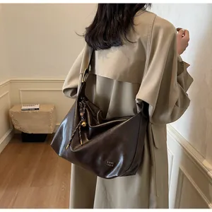 Détail du grand sac cabas en cuir marron foncé avec logo métallique et pendentif décoratif