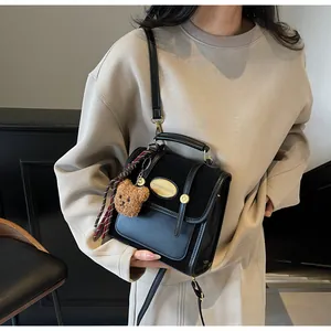 Détail du sac vintage noir montrant le mélange de cuir et le pendentif ours mignon