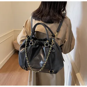 Detail of black pleated cloud bag with gold chain and dual backpack straps on a model