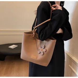 Close-up of caramel leather bucket bag with lychee texture and floral charm detail