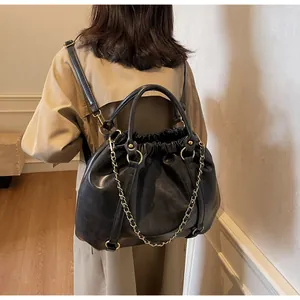 Detail of vintage pleated black leather backpack with gold chain straps and drawstring