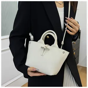 Détail d'un mini sac en cuir blanc cassé avec fermoir style bambou porté par un mannequin