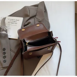 Détails de l'intérieur du sac à bandoulière en cuir marron avec compartiments et fermoirs dorés