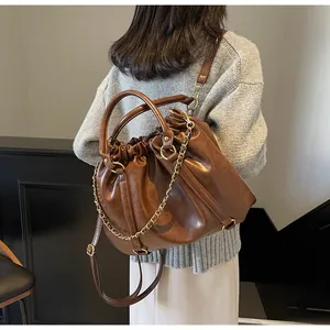 Brown pleated PU leather bag showing soft texture and metal chain detail on model