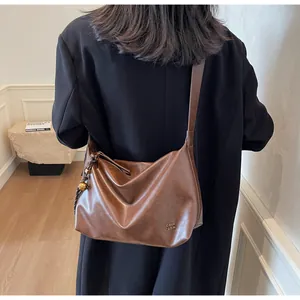 Détail du sac cabas en cuir PU marron souple avec breloque dorée et logo métallique