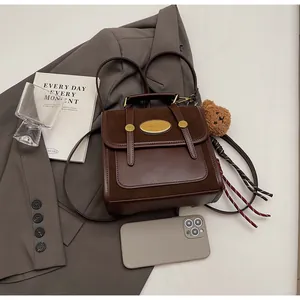 Détails de la petite sacoche marron rétro avec breloque ours et finitions en cuir