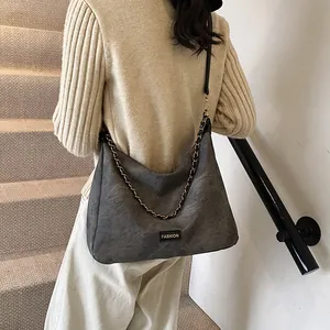 Retro grey suede tote bag with metal chain strap and fashion label shown on model