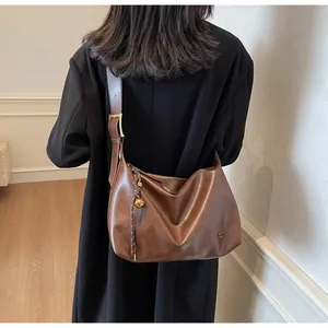 Détail du sac Hobo marron vintage avec large bandoulière et breloque cloche dorée