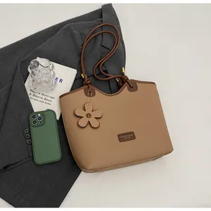 Close-up of brown pebbled leather bucket bag with fashion label and flower charm detail