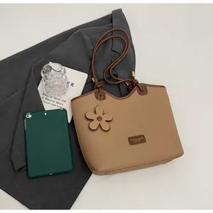 Detail view of khaki faux leather bucket bag with top handle and floral charm detail