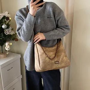 Vintage brown suede tote bag with chain strap shown in a cozy winter setting