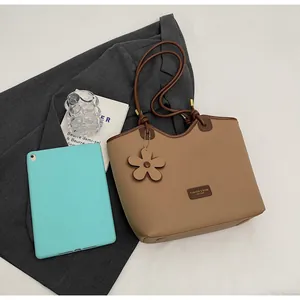 Close-up of brown litchi grain leather bucket bag with fashion tag and flower charm