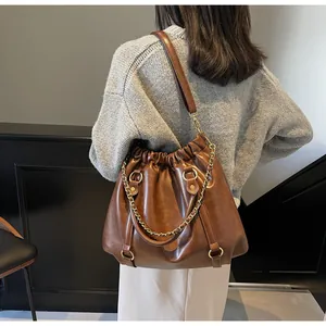 Close-up of vintage brown pleated PU leather bag with gold chain and leather strap