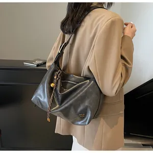Détail d'un cabas gris anthracite souple avec breloque dorée et logo embossé