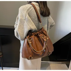 Macro detail of brown pleated leather tote with gold chain and crossbody strap