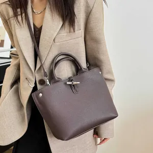 Sac à main marron en cuir avec fermoir bambou porté sur un blazer beige chic