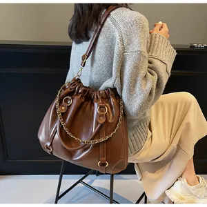 Detail of vintage dark brown pleated bucket bag with gold chain and leather strap