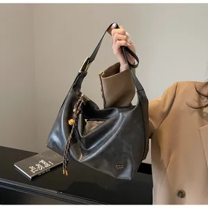 Détail du sac hobo noir avec ferrures dorées et accessoire de cloche tressée
