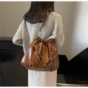 Detail view of brown vintage pleated PU leather tote bag with gold chain and strap
