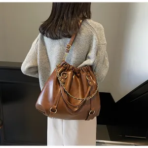 Macro view of vintage brown pleated PU leather tote with a gold metal chain detail