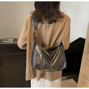 Vue détaillée du grand sac hobo en cuir gris foncé avec un pendentif décoratif en cloche