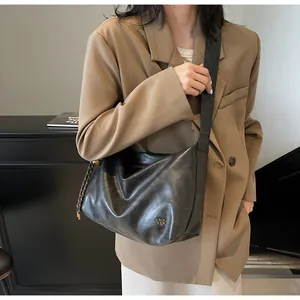 Détail du grand sac cabas noir brillant montrant la texture souple sur un mannequin