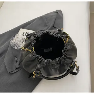 Detail view of the black pleated handbag interior with a zipper pocket and gold chain handle