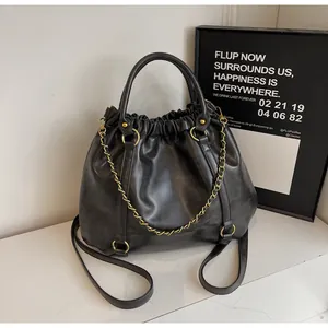 Close-up of black pleated faux leather bag showing soft texture and gold chain strap