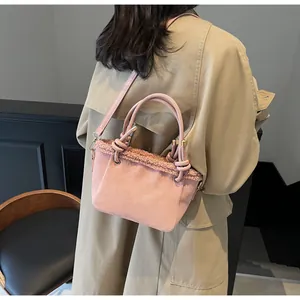 Detail of pink matte bucket bag with teddy fur trim carried by a model in a trench coat