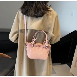 Detailed back view of pink matte bucket bag with fur trim on khaki trench coat