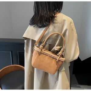 Detail view of brown suede bucket bag with faux fur trim and gold hardware on model