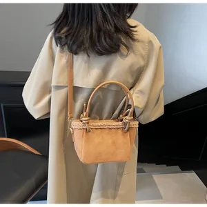 Detail of a brown suede bucket bag with shearling trim worn with a beige trench coat